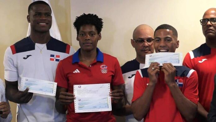 Cristian Pinales, Marileidy Paulino y Yunior Alcántara muestran los cheques de sus bonos millonarios recibidos por el desempeño realizado en los Juegos Olímpicos 2024. (CORTESÍA MIDEREC)